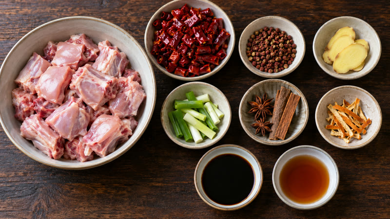 Rabbit pieces arranged separately from dried chilies, Sichuan peppercorns, ginger, scallions, and whole spices