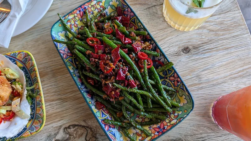 Sichuan Dry Fried Green Beans Recipe: Texture, Heat, and Stir-Fry Steps 2 Green beans and minced meat with red pepper pieces on a patterned platter