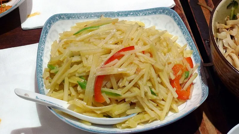 Julienned potatoes with red and green pepper strips on a blue-bordered plate