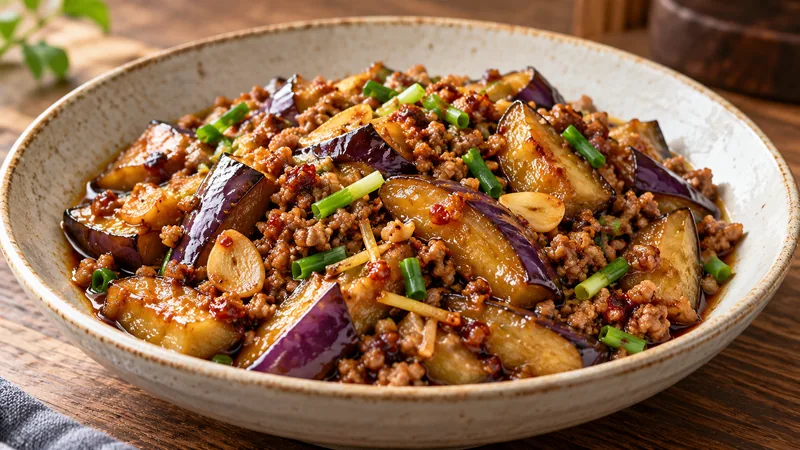 Sichuan Eggplant Recipe: Sauce, Texture, and Timing Checks 1 Soft skin-on purple eggplant pieces with browned pork mince, sliced garlic, ginger and scallion in a red-brown coating