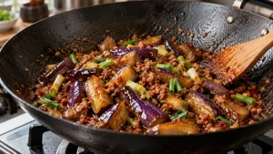 Tender seared eggplant and cooked minced pork simmering in glossy doubanjiang sauce with scallions in a black wok