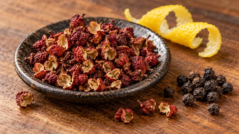Sichuan Peppercorn Substitute: Flavor Tradeoffs and Safe Ratios 1 Opened red Sichuan pepper husks beside black peppercorns and lemon peel